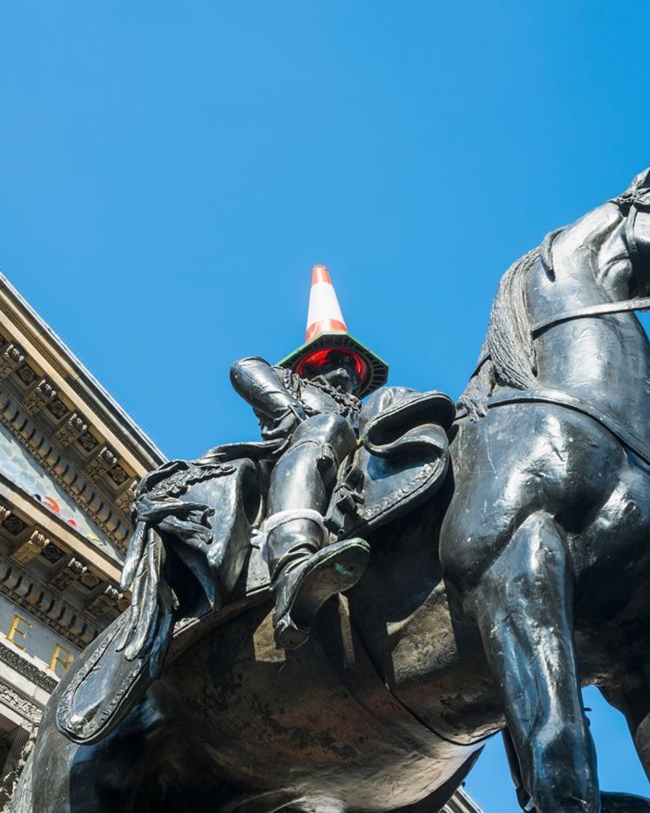 Monument of a man riding a horse positioned before an impressive structure, symbolizing heritage and artistry.