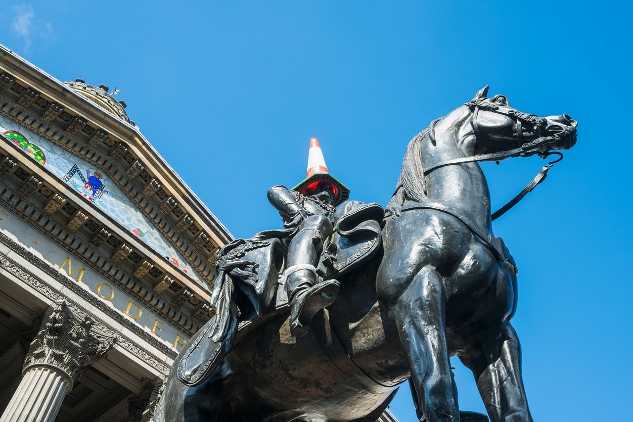 Monument of a man riding a horse positioned before an impressive structure, symbolizing heritage and artistry.