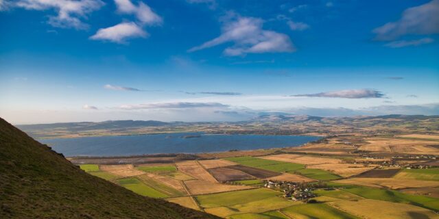 The view towards Loch Leven overlooking fields from a hilltop