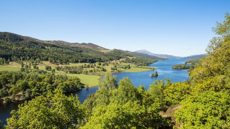 Blue skies on a summer day stretching across a winding blue river surrounded by lush green trees and Scottish hills