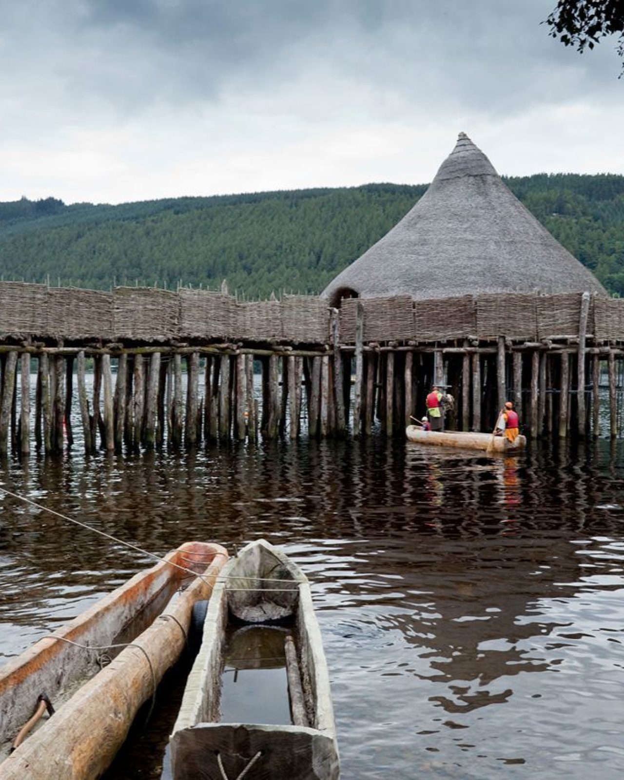 Wooden boats on Scottish loch in front of ancient crannog structure