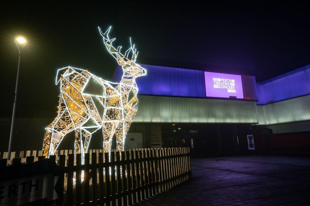 A model of a stag lit up on a dark night with Perth Theatre in the background