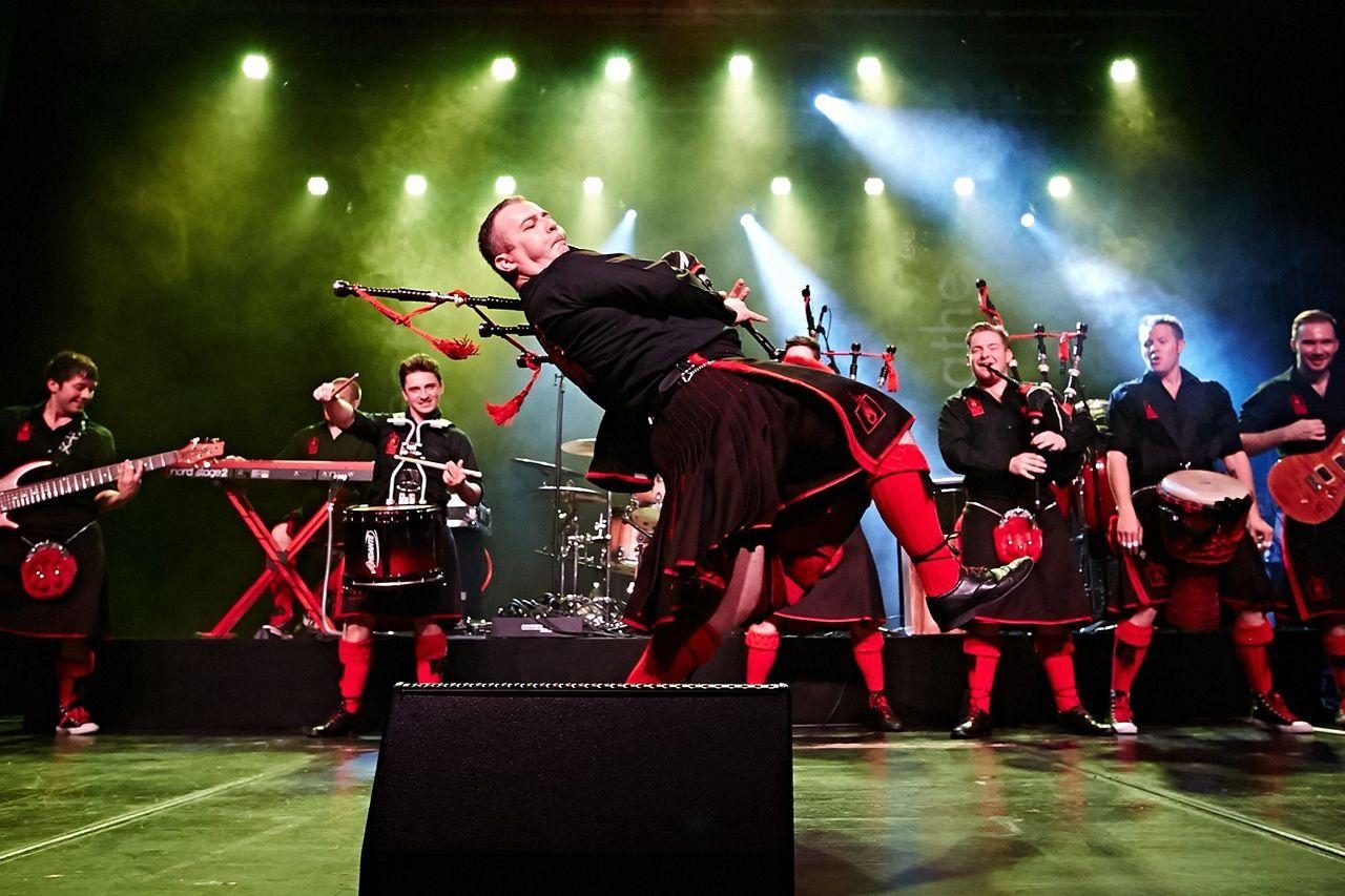 a band of people wearing kilts and playing bagpipes on a big stage