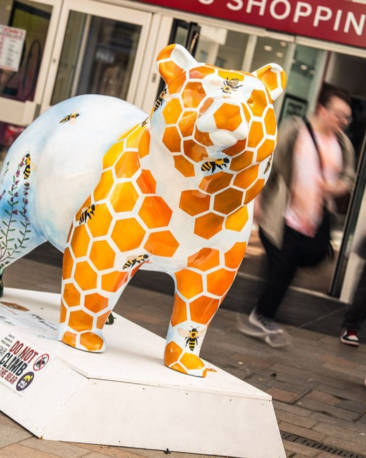 A ceramic bear which has honeycomb, bees and flowers painted around it.