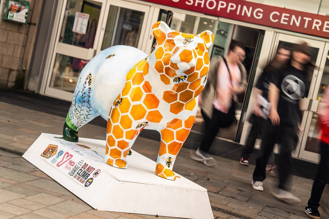 A ceramic bear which has honeycomb, bees and flowers painted around it.