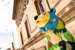 A colourful bear with different woodland animals enjoying a meadow
