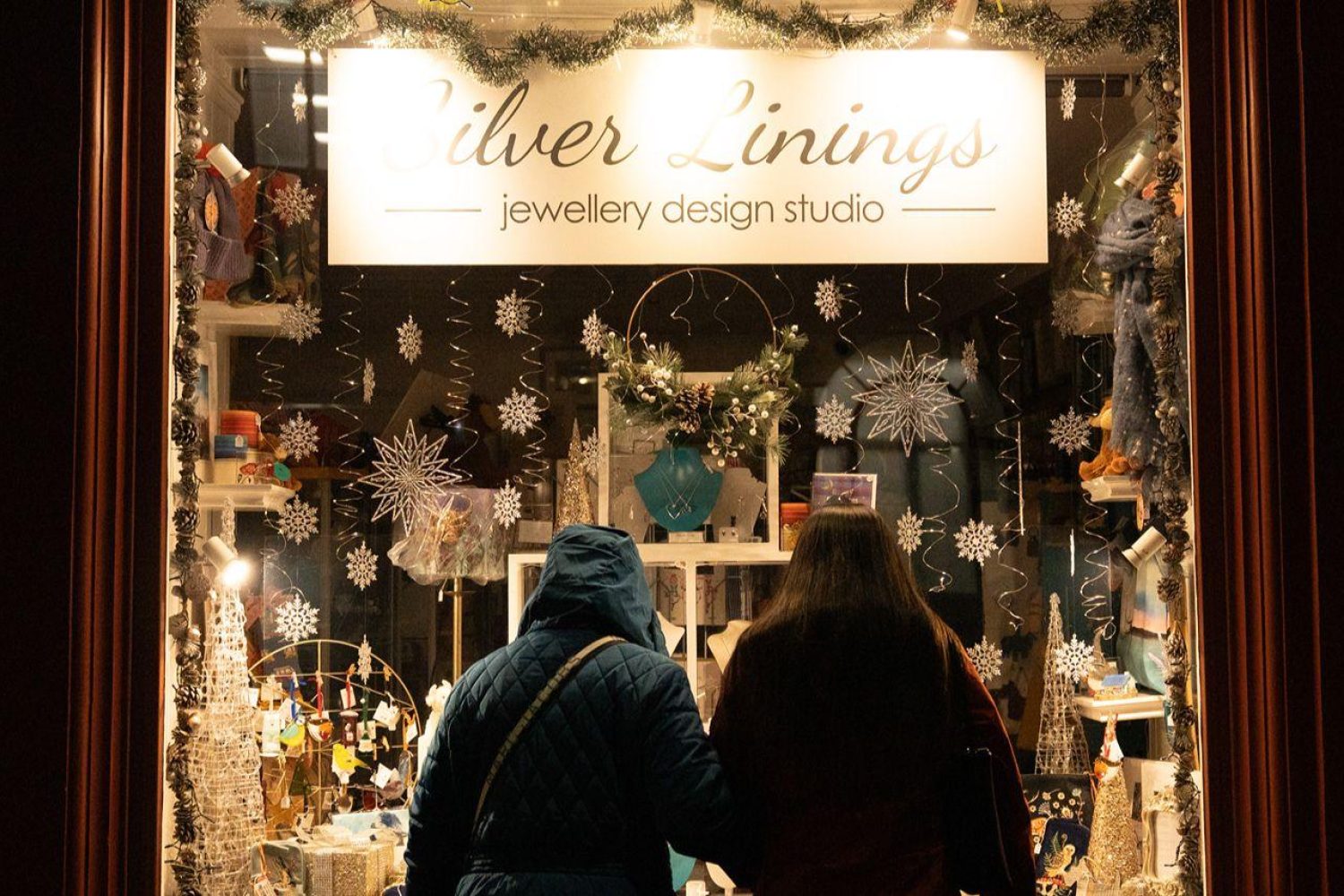 A beautiful Christmas shopping window with two women looking in.