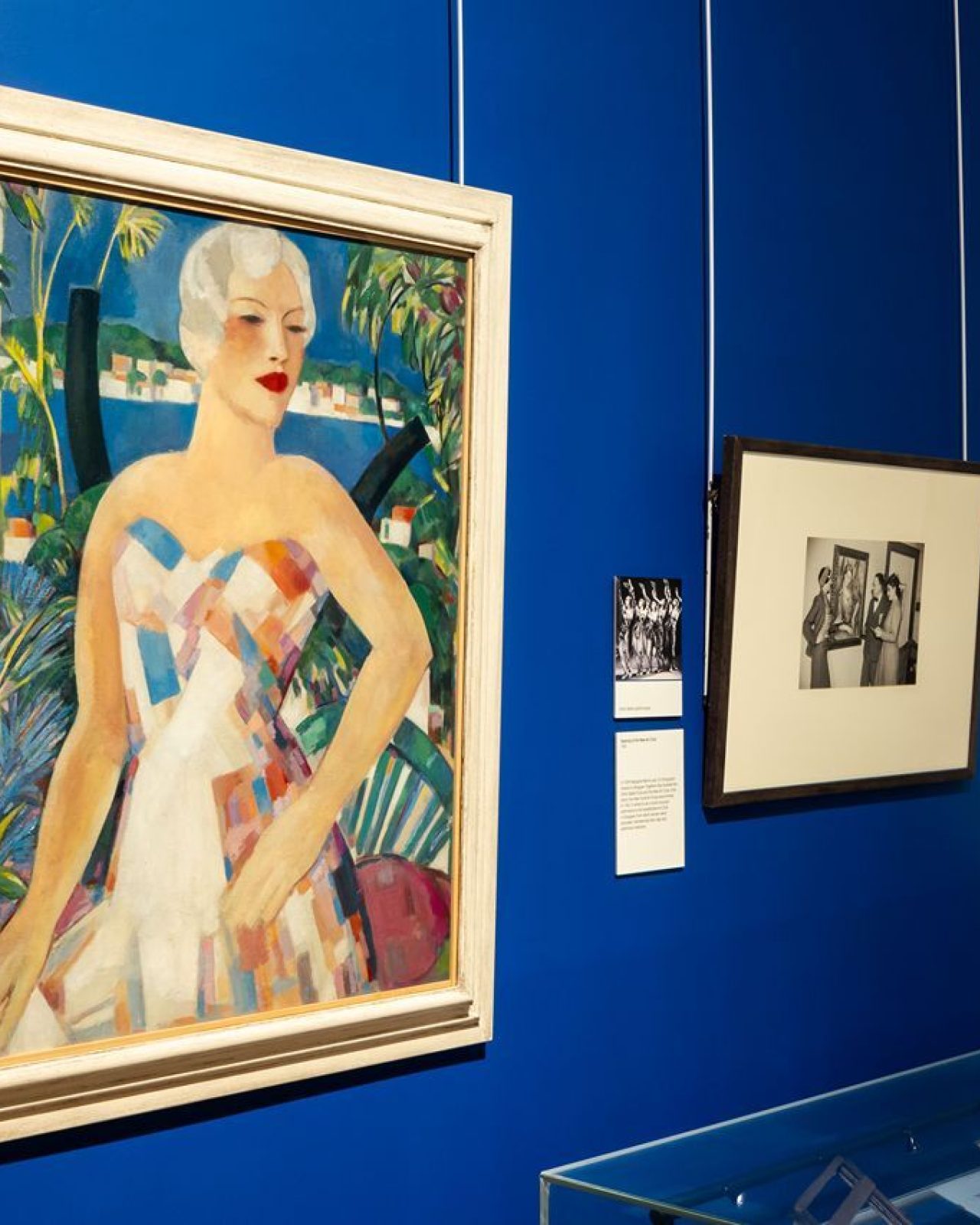 Brightly coloured painting of a woman hanging on a bright blue wall
