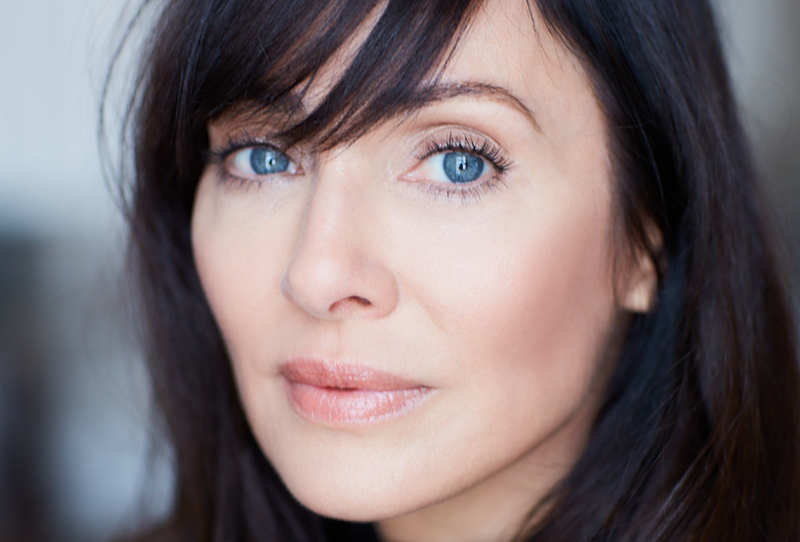 Dark haired woman, with large pale blue eyes.