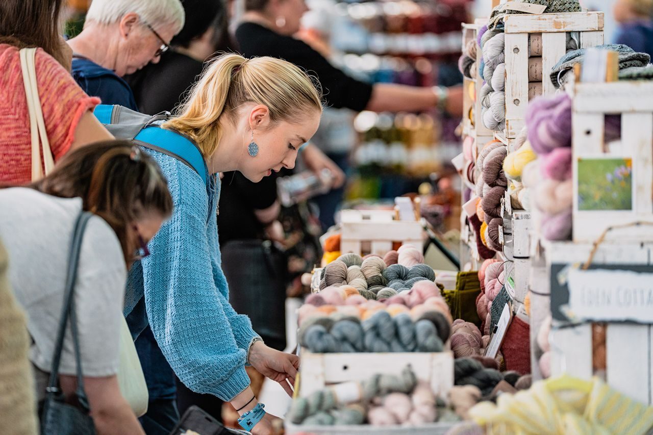 People looking at lots of different coloured wools in crates.