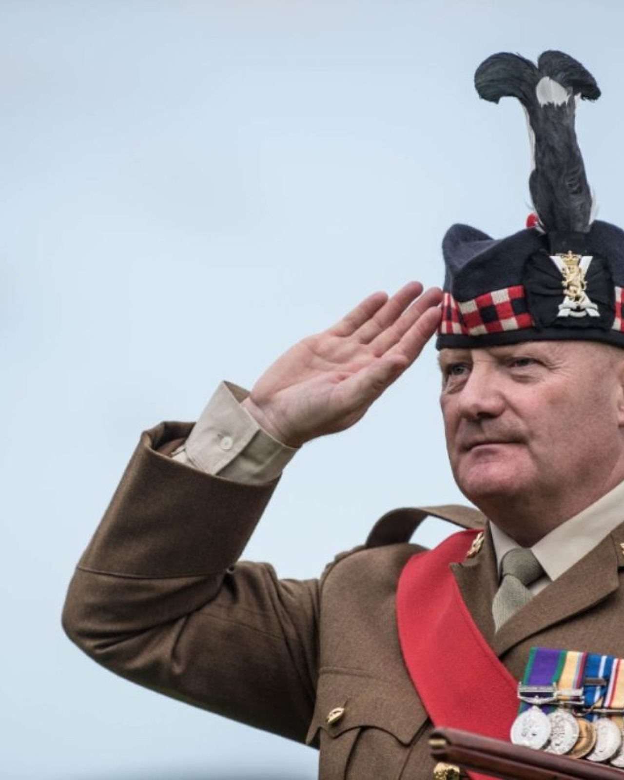 A man wearing military uniform saluting.