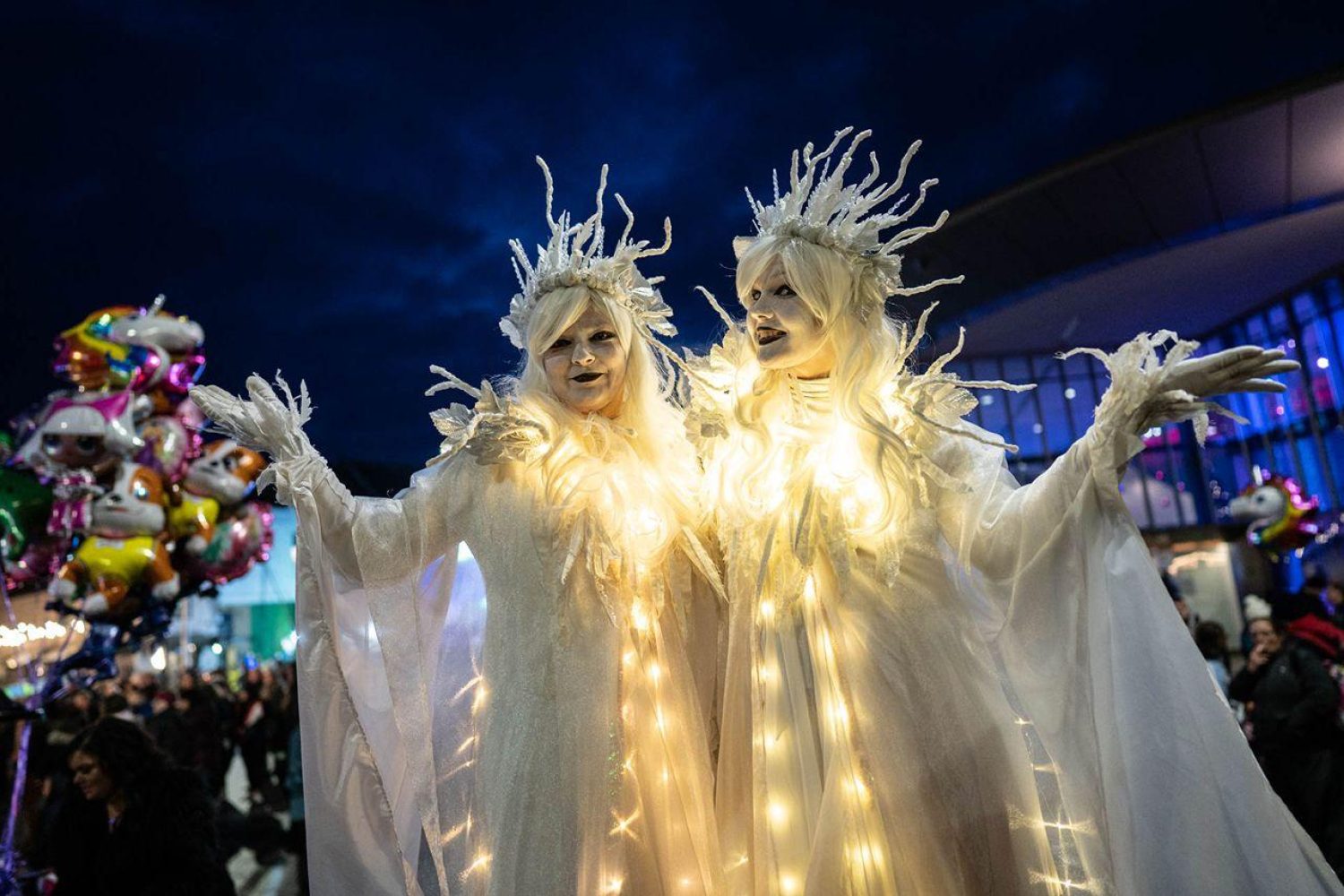 two street entertainment women in magical white floating gowns with crowns