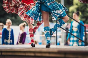 two sets of women's legs dancing the highland fling, one in red socks and one in blue socks