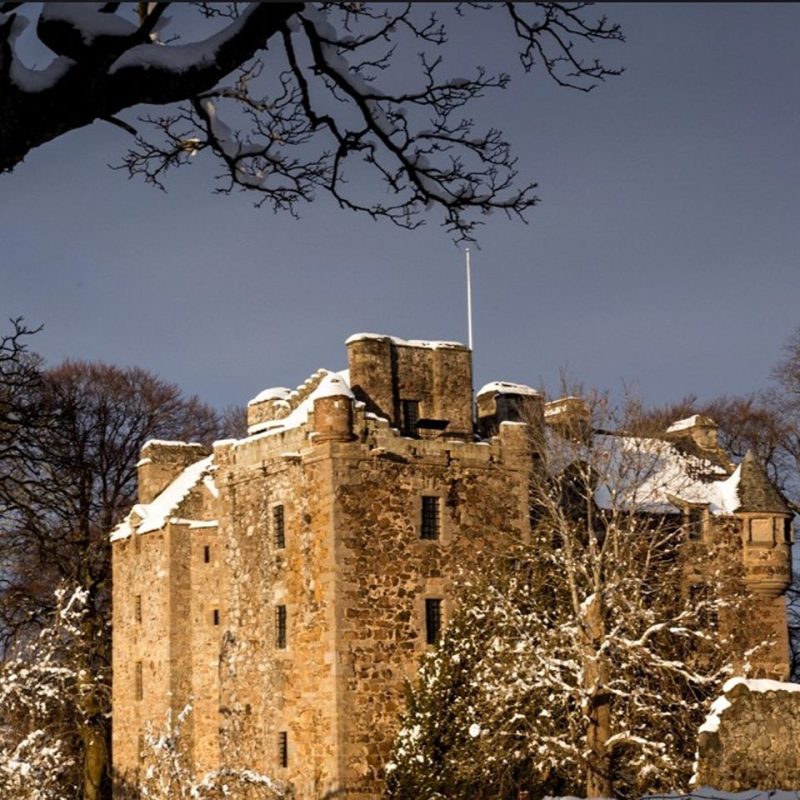 Old stone large castle, on a winters day with snow on roof.