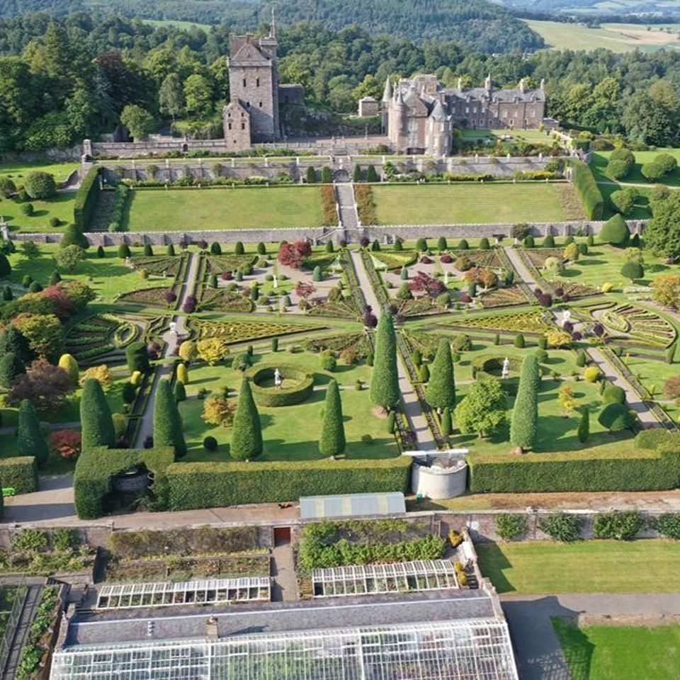 Large formal gardens with an old stone building in the distance