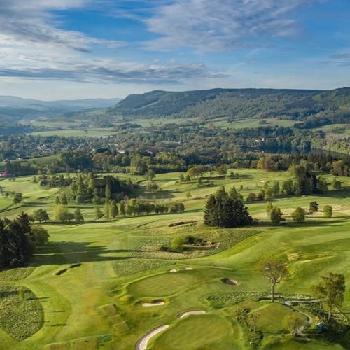 Ariel view of a green golf course surrounded by trees and hills in the distance, blue sky with some ewehit5e clouds, Pitlochry Golf Course.