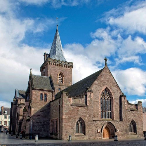 Large old stone church with tall spire under a blue skiy