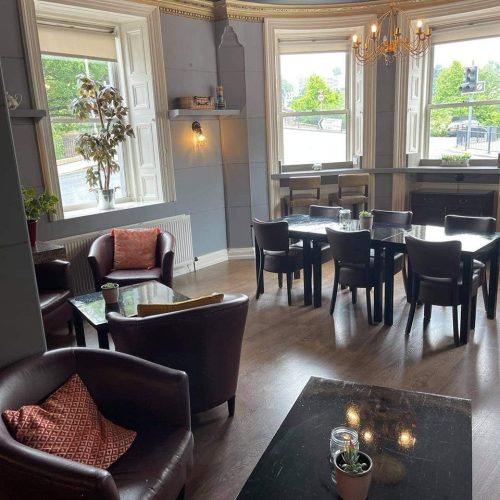Large pale blue room with tables and chairs and three windows, Cafe 80 in Perth