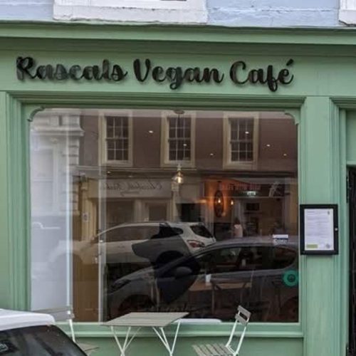 A light green building with a black sign which reads 'Rascals vegan cafe'