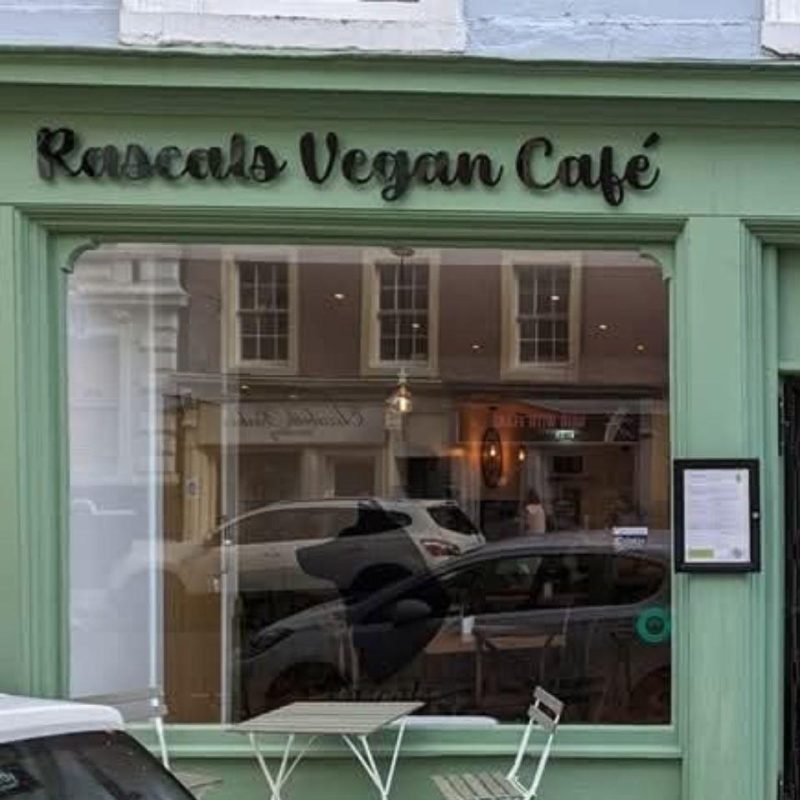 A light green building with a black sign which reads 'Rascals vegan cafe'
