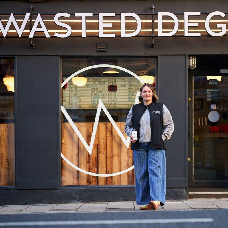 Smiling woman standing in front of Wasted Degrees Pub.