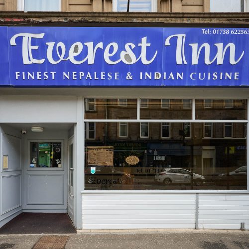 A white building with a blue sign which reads 'Everest Inn Finest Nepalese & Indian Cusine'