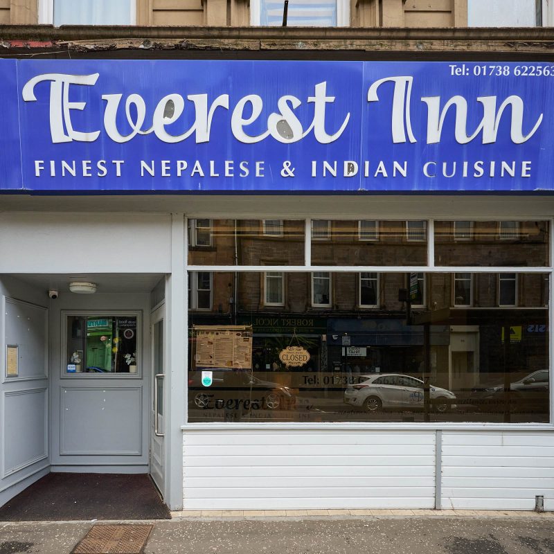 A white building with a blue sign which reads 'Everest Inn Finest Nepalese & Indian Cusine'