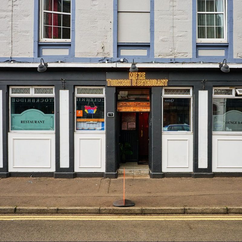 White and black painted restaurant with signage for Meze Turkish Restaurant.