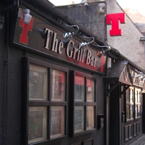Black painted bar front , with a red T sign and The Grill bar in silver letters.
