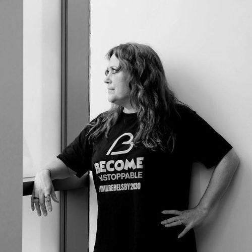 A woman looking out the window wearing a black tshirt which says 'become unstoppable'