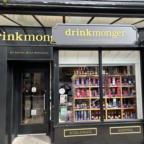 A black shop with a gold sign which reads 'Drinkmonger'