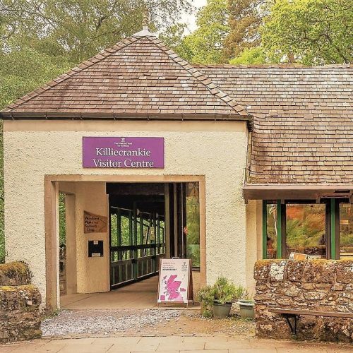 Open yellow building with viewing platform , signage says Killiecrankie Visitor Centre , nestled in the trees