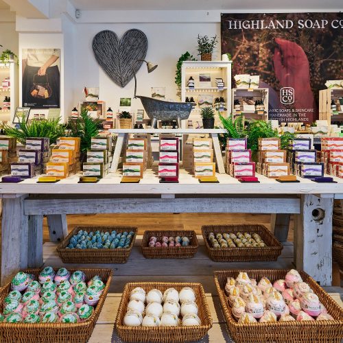 A wooden table with different kinds of soaps displayed on it.