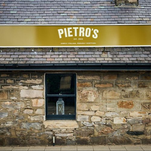 Old stone cottage with window and slate roof with signage for Pietro's Italian restaurant