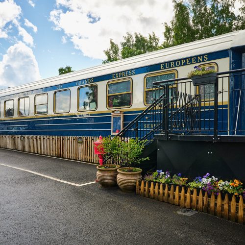 An old white and blue train on a platform which has been converted into a restaurant.