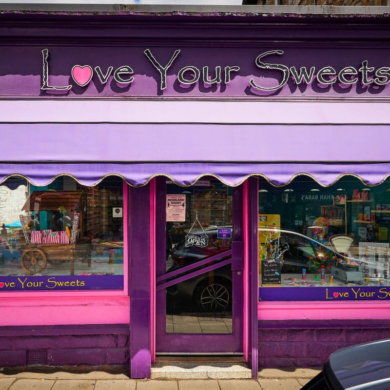 A pink and purple shop with a sign which says 'Love Your Sweets.'