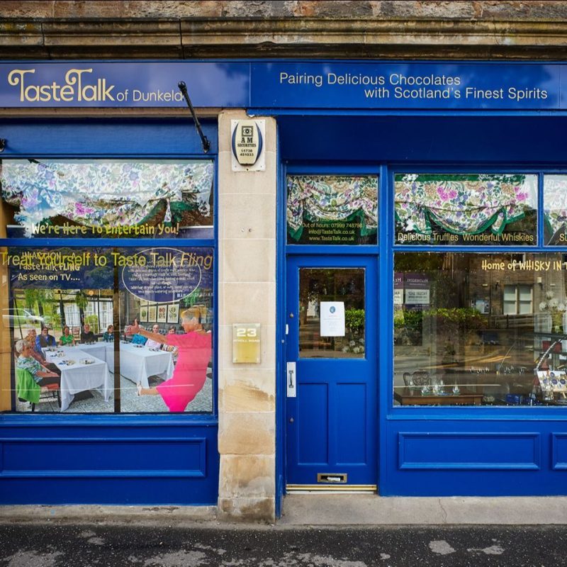 Blue painted signage and door for Taste Talk Dunkeld, on a shop front advertising pairing chocolate with spirits.