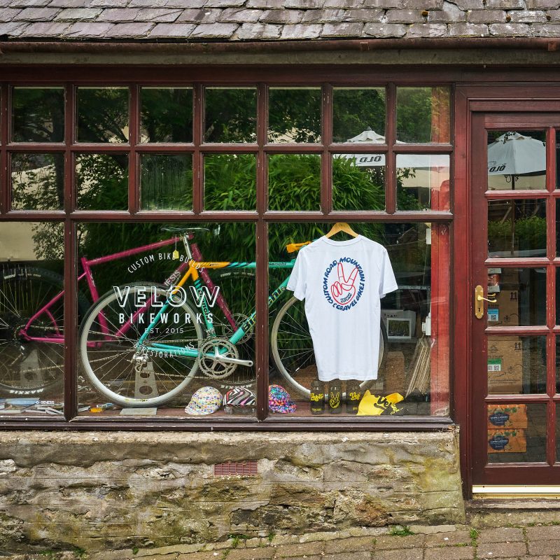 A brick shop with a blue and a pink bike in the window.