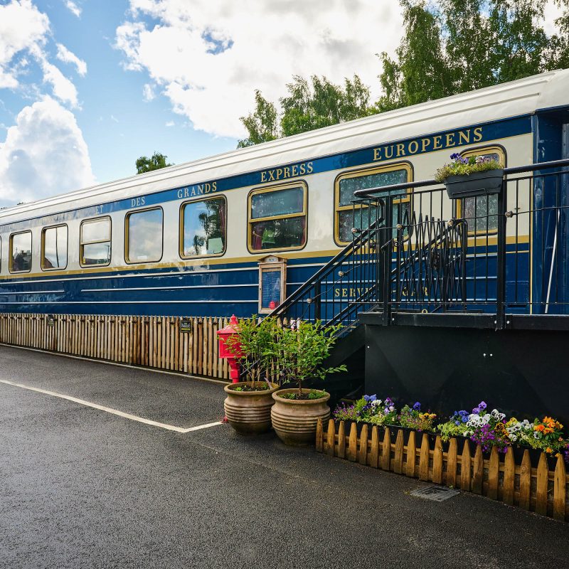 An old white and blue train on a platform which has been converted into a restaurant.