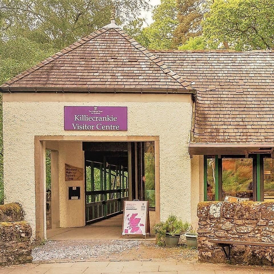 Open yellow building with viewing platform , signage says Killiecrankie Visitor Centre , nestled in the trees