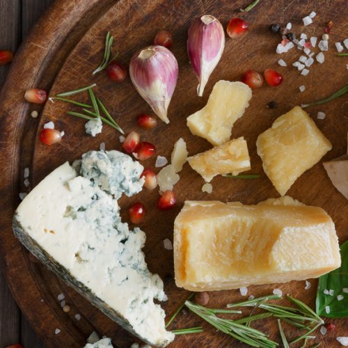 Wooden board with a variety of cheese and shallots and herbs