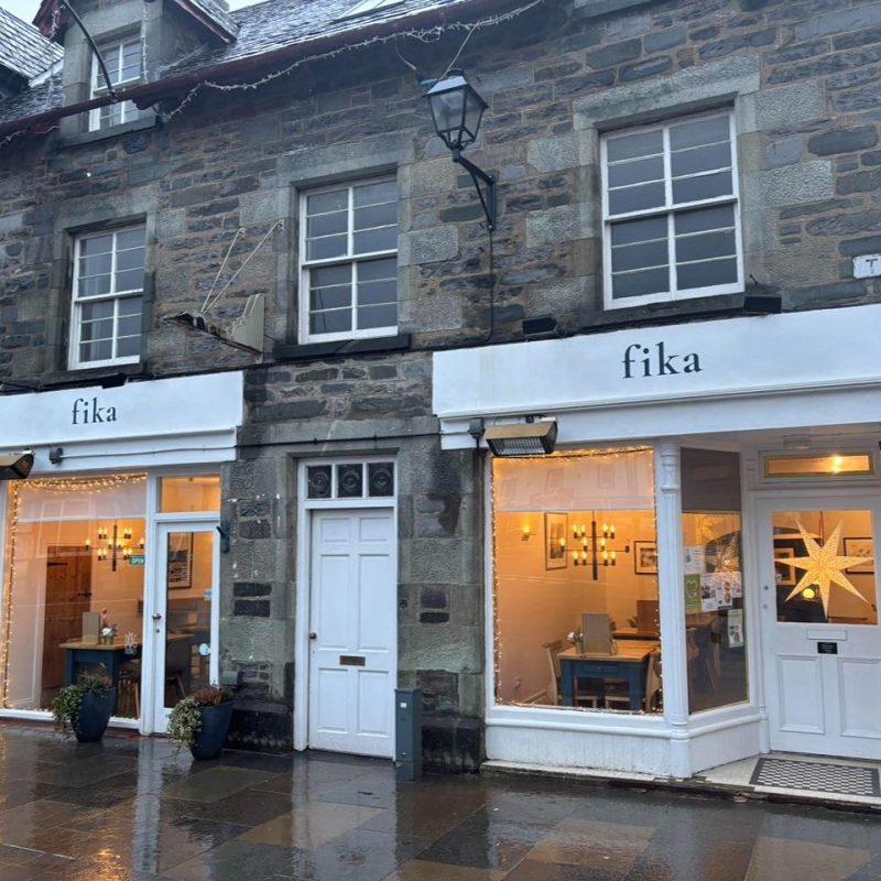 Shop front with two large bay windows with cream paint and sign above the two windows saying Fika