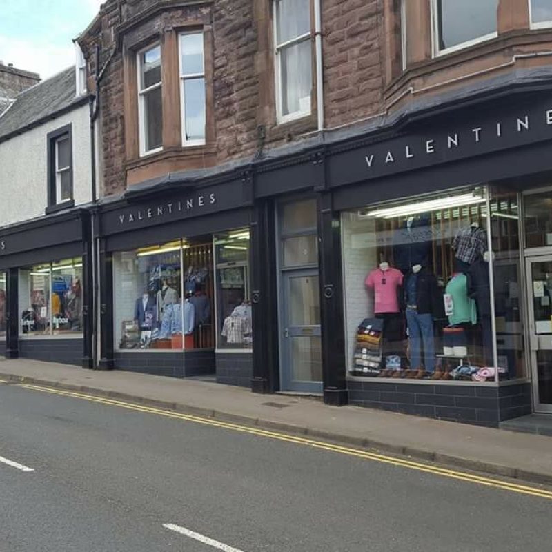 Large shop with painted black trim, large windows displaying clothes and signage that says Valentines of Crieff