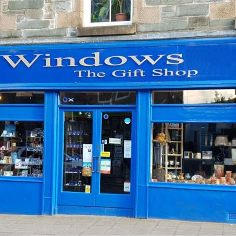 Royal blue shop front displaying cards, pictures, ornaments sign above door says Windows the gift shop