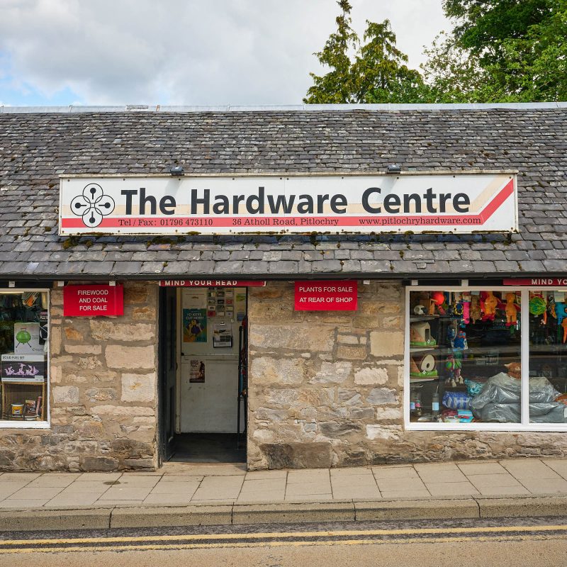 A brick building with a white and red sign which reads 'The Hardware Centre'