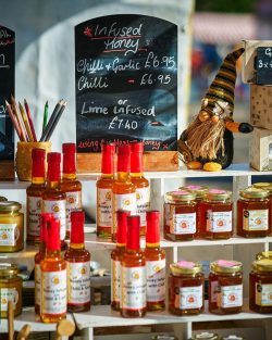 Bottles and jars on a shelving display, Cloverlea honey infused with chilli, at Perth farmers Market