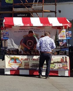 Market stall with red and white stripes, person browsing at goods.