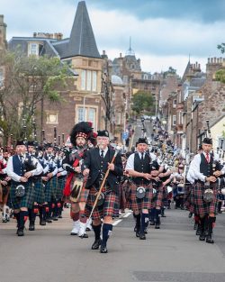 Pipe band marching, wearing Kilts and Scottish attire down Market street in Crieff