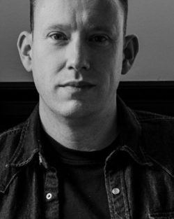 Black and white picture of a man staring solemnly into camera