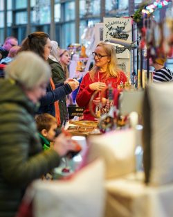 A bustling Christmas Market with lots of people and gifts